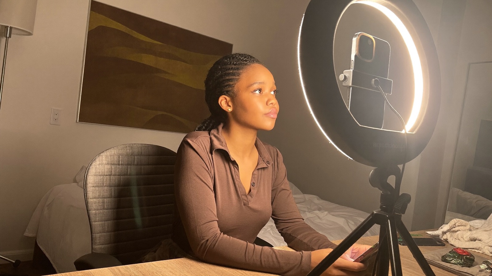 Behind the scenes of a correct setup: a ring light with a phone mounted in the center placed in front of the model, slightly above eye level, her face evenly lit