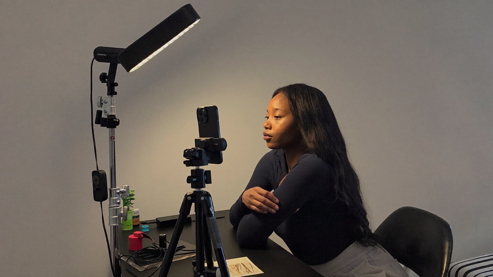 Behind the scenes of a correct setup: an LED light on a stand raised above eye level and placed off to the model's side at forty five degrees, angled down onto her face